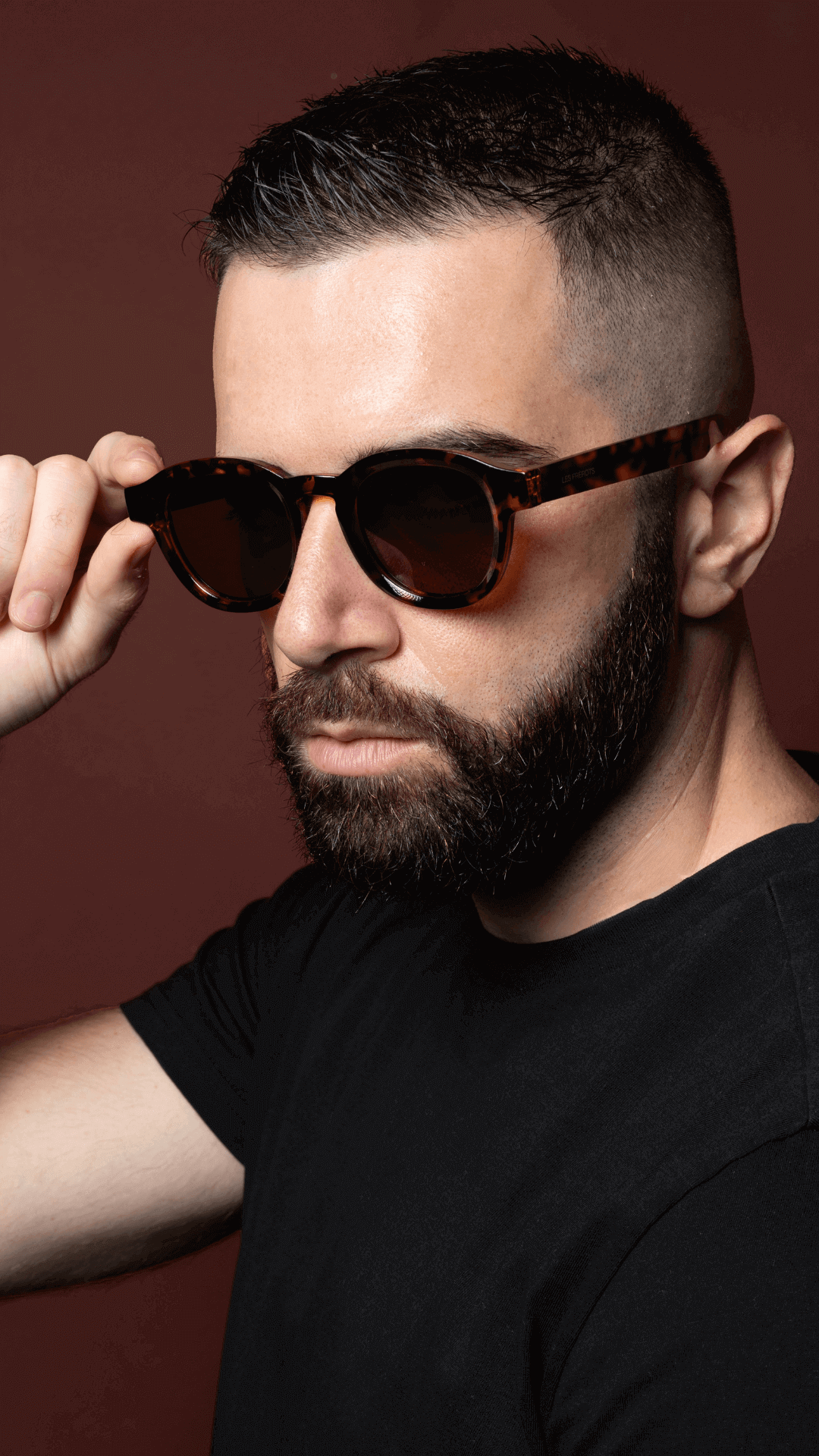 Male model wearing black vintage oval sunglasses, slight left downside angle