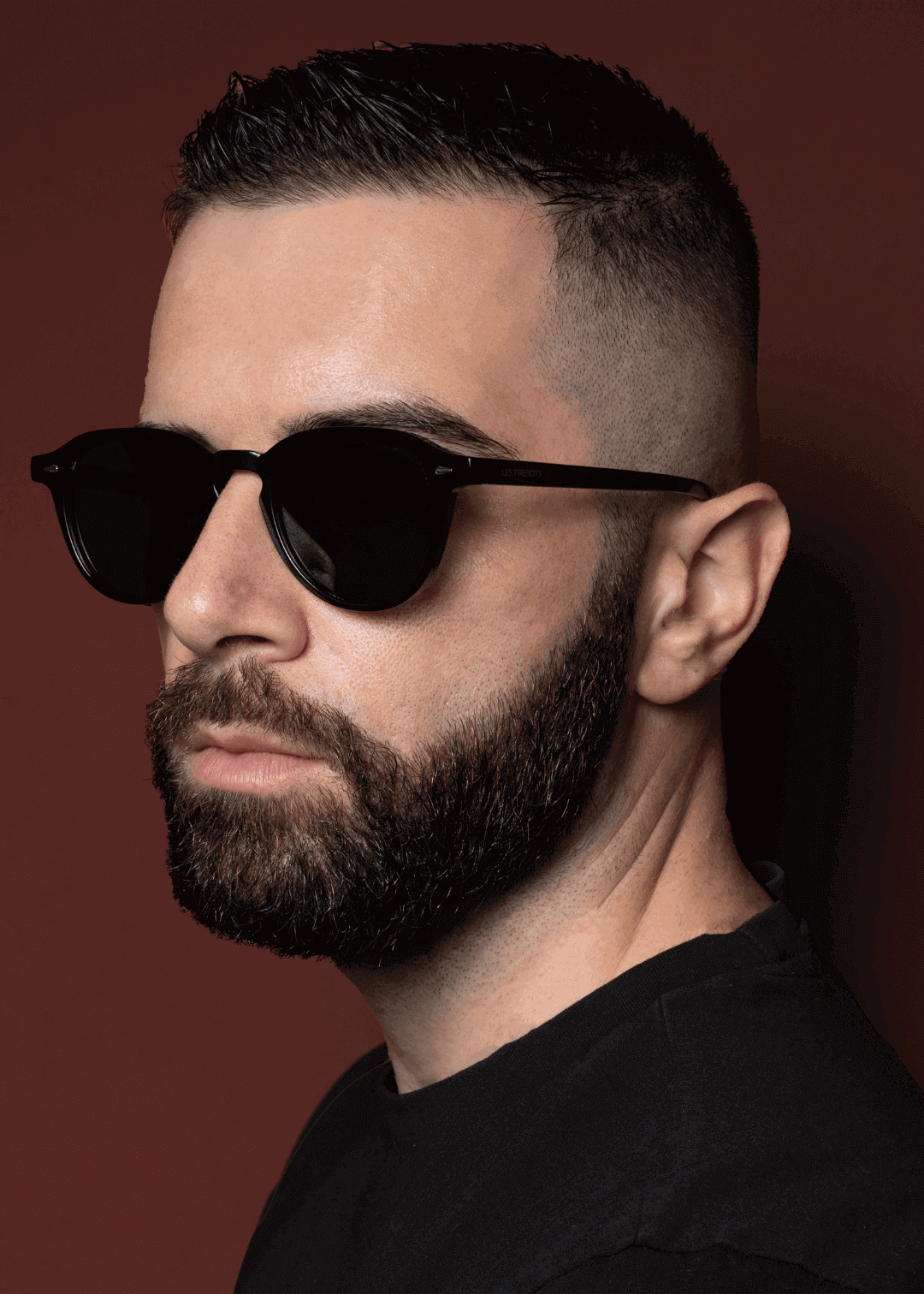 Male model is wearing black oval sunglasses, slight left side angle 