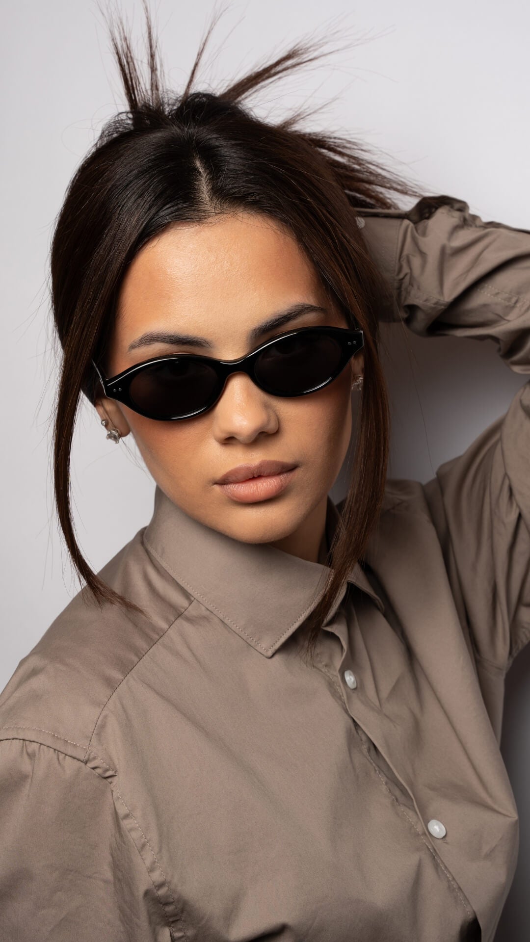 female model wearing black oval sunglasses, head slightly tilted downside, front angle